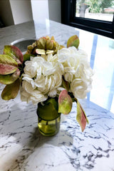 The beloved Hydrangea is celebrated in this magnificently timeless display that will suit all interiors.  Large white and green hydrangea flower heads have been individually arranged  by our skilled team of florists with foliage in a sleek, green green vase.   UNBOX & ENJOY The deceptively realistic stems can be delivered arranged in a green glass vase or as a beautifully wrapped bouquet.  The perfect gift for your home or to give to a loved one.