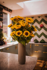 A modern Autumnal faux flower arrangement of finest quality faux sunflower stems which our team of florists have arranged into a modern white ceramic vase