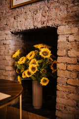 A modern Autumnal faux flower arrangement of finest quality faux sunflower stems which our team of florists have arranged into a modern white ceramic vase