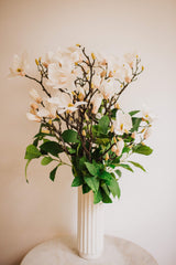 Large luxury faux floral arrangement of magnolia flowers and foliage arranged in a tall off-white vase or available as a gift wrapped bouquet.  Perfect for businesses, large spaces in a home or as a gift.