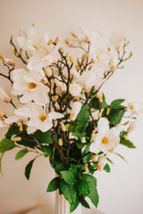 Large luxury faux floral arrangement of magnolia flowers and foliage arranged in a tall off-white vase or available as a gift wrapped bouquet.  Perfect for businesses, large spaces in a home or as a gift.
