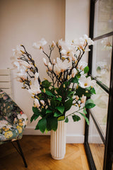 Large luxury faux floral arrangement of magnolia flowers and foliage arranged in a tall off-white vase or available as a gift wrapped bouquet.  Perfect for businesses, large spaces in a home or as a gift.