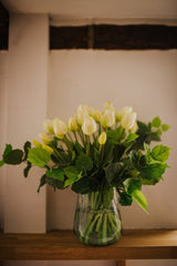 Luxury artificial white tulips and green salal foliage expertly arranged by our team of florists into a choice of light green glass or taupe metal vase or available as a beautifully wrapped bouquet.