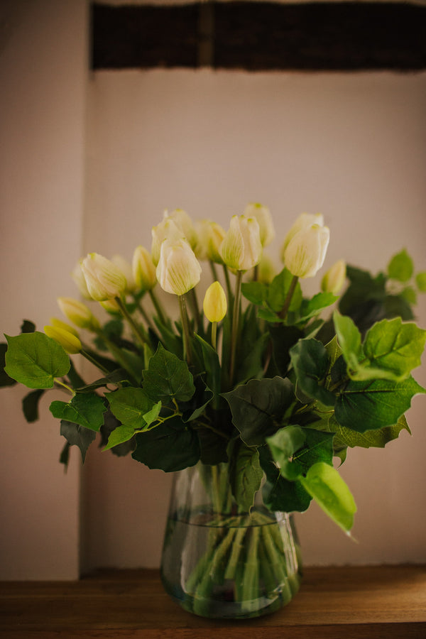 Luxury artificial white tulips and green salal foliage expertly arranged by our team of florists into a choice of light green glass or taupe metal vase or available as a beautifully wrapped bouquet. 