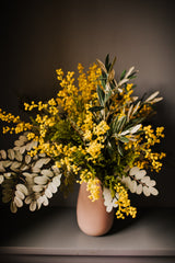 An abundance of artificial mimosa, olive branches and soft grey foliage arranged in a chic off white vase or available as a gift wrapped bouquet.  Perfect for the home or to gift.