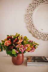 Artificial pink hellebores arranged with foliage into a sleek blush pink vase or available as a gift wrapped bouquet.  Perfect for home or to gift!