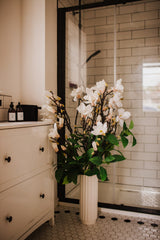 Large luxury faux floral arrangement of magnolia flowers and foliage arranged in a tall off-white vase or available as a gift wrapped bouquet.  Perfect for businesses, large spaces in a home or as a gift.