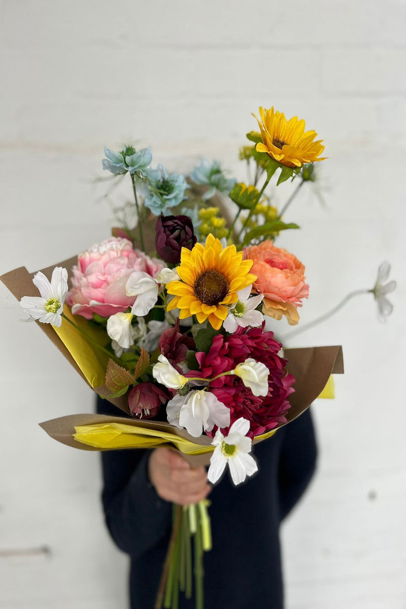 A bold burst of candy coloured blooms, our Jay bouquet blends irresistible shades of  ranunculus, tulips, hellebore, sunflowers, cosmos, sweet peas, yarrow and nigella.     Hand-tied by our team of expert florists ready to bring your vase to life!