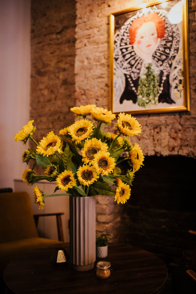 A modern Autumnal faux flower arrangement of finest quality faux sunflower stems which our team of florists have arranged into a modern white ceramic vase