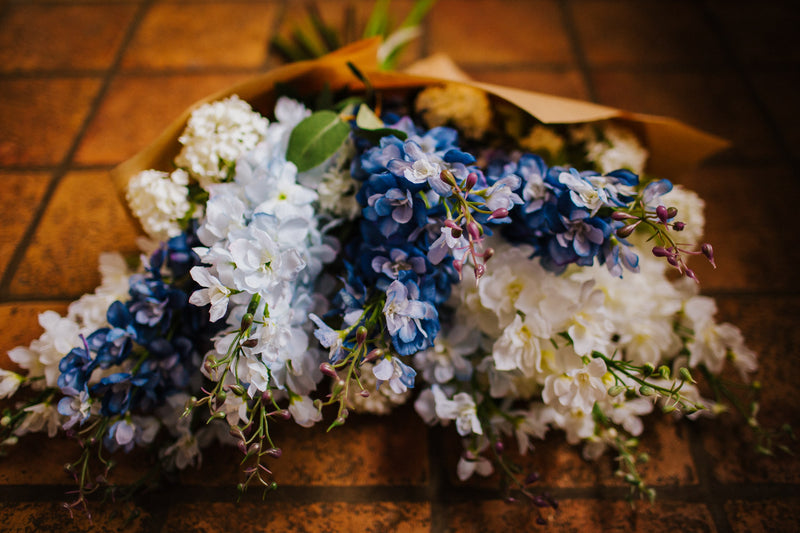 Luxury artificial delphinium, viburnum Snowball and salal foliage expertly arranged by our team of florists into a ceramic vases or available as a beautifully wrapped bouquet. Perfect for corporate and larger spaces.