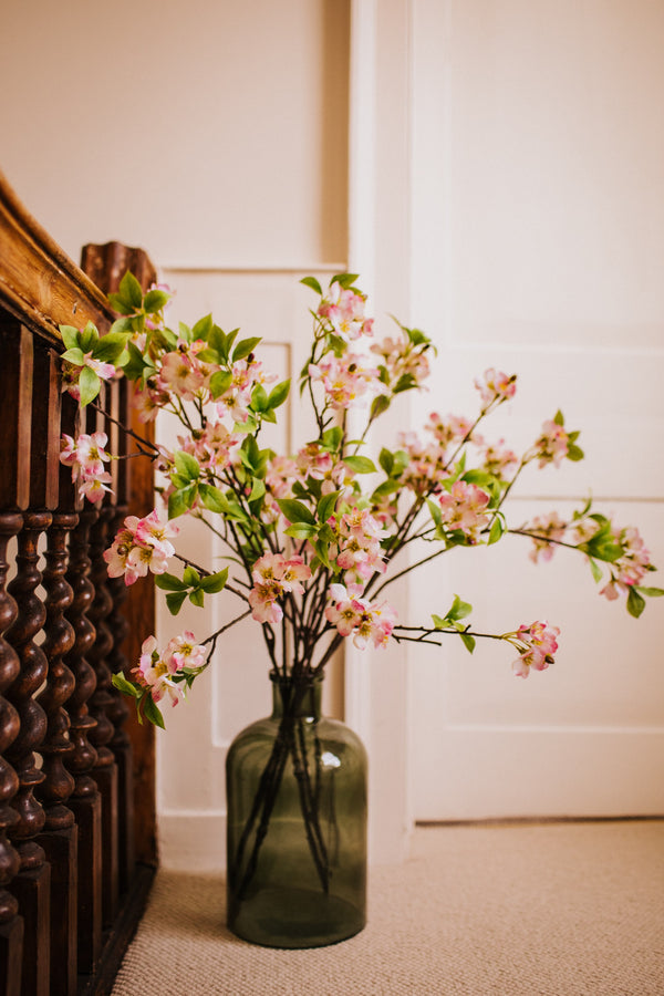 Deceptively realistic artificial pink blossom styled in a bottle vase by our team of expert florists to be enjoyed from every angle or available as a gift wrapped bouquet.