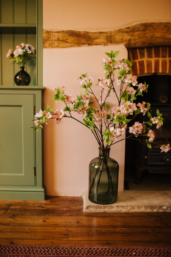 Deceptively realistic artificial pink blossom styled in a bottle vase by our team of expert florists to be enjoyed from every angle or available as a gift wrapped bouquet.
