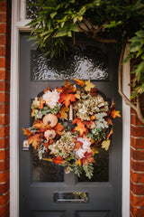 An eye catching abundance of autumnal foliage paired with silky cream and blush pink hydrangea, blooms and pumpkins in a celebration of the amazing colours and textures of the season.    This luxurious faux wreath has been created by our team of skilled florists ready to add instant warmth and comfort to any space.